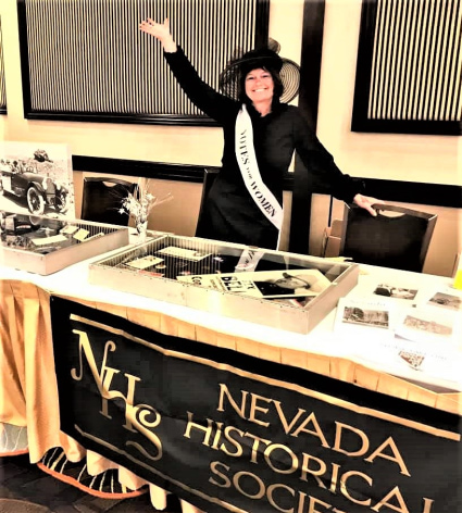 a person in a black hat standing in front of a table with a sign